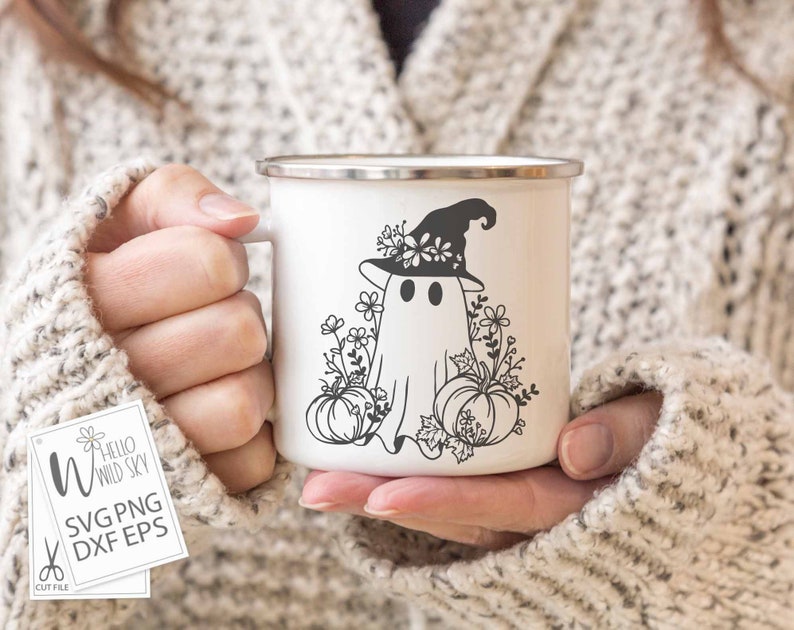 May include: A white enamel mug with a black and white illustration of a ghost wearing a witch hat with flowers. The ghost is surrounded by pumpkins and flowers.