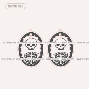 May include: Two black and white Halloween-themed oval pendants. Each pendant features a skull and rib cage design within a decorative frame. The text "HELLO WILD SKY" is repeated around the oval. The text "INFOR FILE" is at the top.