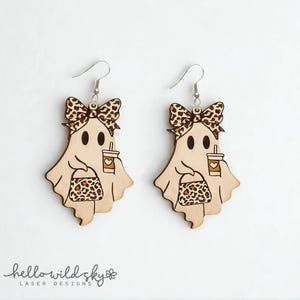 Puede incluir: Un par de pendientes de fantasma de madera con lazo, taza de café y bolso, todos con diseño de estampado de leopardo. Los pendientes están cortados con láser y tienen ganchos plateados. Sobre un fondo blanco.