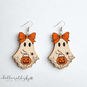 May include: Wooden ghost earrings with orange bow, eyes, and pumpkin. The earrings have a spider and web design. The earrings are laser cut and have a silver hook.