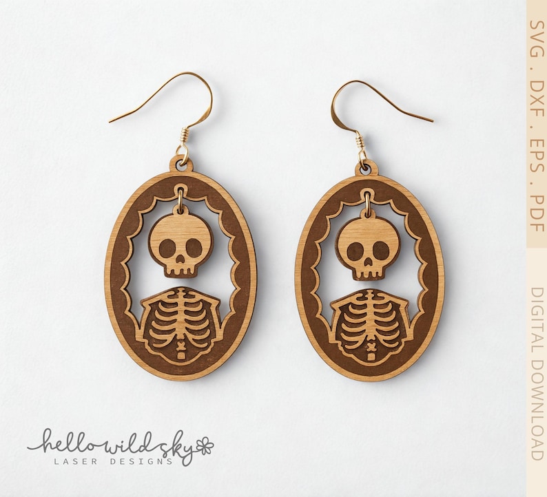 May include: A pair of wooden skeleton earrings. Each earring features a skull and rib cage design within an oval frame. The earrings are light brown with gold-colored ear wires. The text "hello wild sky laser designs" is at the bottom.