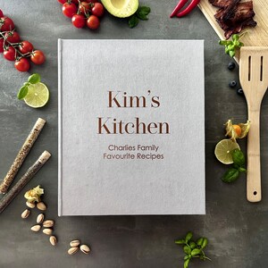 Handcrafted Light gray cover color with foil copper lettering color personalized recipe book and binder, covered in soft fabric and made with high-quality materials. Designed to organize and preserve handwritten family recipes, this elegant cookbook serves as a timeless keepsake. Perfect for saving cherished meals, holiday dishes, and family traditions, it makes a thoughtful and lasting gift for home cooks who treasure the joy of sharing meals together.