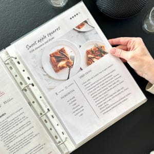 Personalized custom ring binder recipe book with hard cover and printed pages. Features recipe journal pages with sections for recipe name, prep time, cook time, servings, ingredients, directions, and notes. Includes 16 category dividers, 10 notes pages, 20 transparent sleeves, and one clear envelope sheet for small notes. Perfect for saving cherished meals, holiday dishes, and family traditions — a thoughtful gift for home cooks who love sharing meals together.