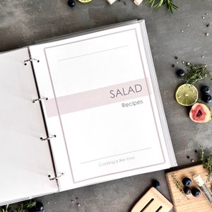 Personalized custom ring binder recipe book with hard cover and printed pages. Features recipe journal pages with sections for recipe name, prep time, cook time, servings, ingredients, directions, and notes. Includes 16 category dividers, 10 notes pages, 20 transparent sleeves, and one clear envelope sheet for small notes. Perfect for saving cherished meals, holiday dishes, and family traditions — a thoughtful gift for home cooks who love sharing meals together.