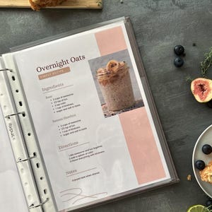 Personalized custom ring binder recipe book with hard cover and printed pages. Features recipe journal pages with sections for recipe name, prep time, cook time, servings, ingredients, directions, and notes. Includes 16 category dividers, 10 notes pages, 20 transparent sleeves, and one clear envelope sheet for small notes. Perfect for saving cherished meals, holiday dishes, and family traditions — a thoughtful gift for home cooks who love sharing meals together.