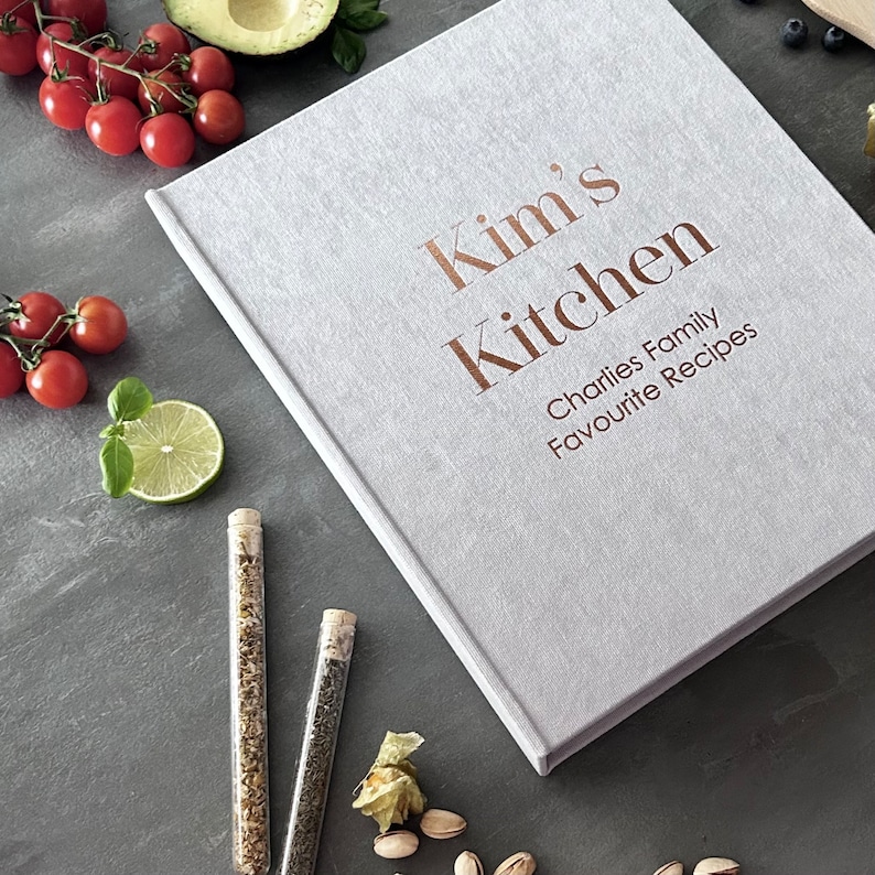 Handcrafted Light gray cover color with foil copper lettering color personalized recipe book and binder, covered in soft fabric and made with high-quality materials. Designed to organize and preserve handwritten family recipes, this elegant cookbook serves as a timeless keepsake. Perfect for saving cherished meals, holiday dishes, and family traditions, it makes a thoughtful and lasting gift for home cooks who treasure the joy of sharing meals together.
