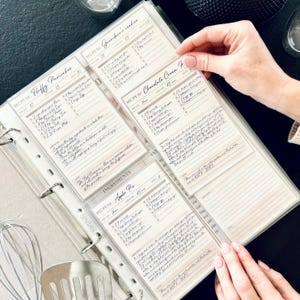 Personalized custom ring binder recipe book with hard cover and printed pages. Features recipe journal pages with sections for recipe name, prep time, cook time, servings, ingredients, directions, and notes. Includes 16 category dividers, 10 notes pages, 20 transparent sleeves, and one clear envelope sheet for small notes. Perfect for saving cherished meals, holiday dishes, and family traditions — a thoughtful gift for home cooks who love sharing meals together.