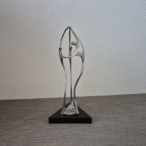 Corry Ammerlaan-van Nieuwkerk – Escultura de bronce y hojalata 'Colaboración' sobre base triangular de granito (29 cm)