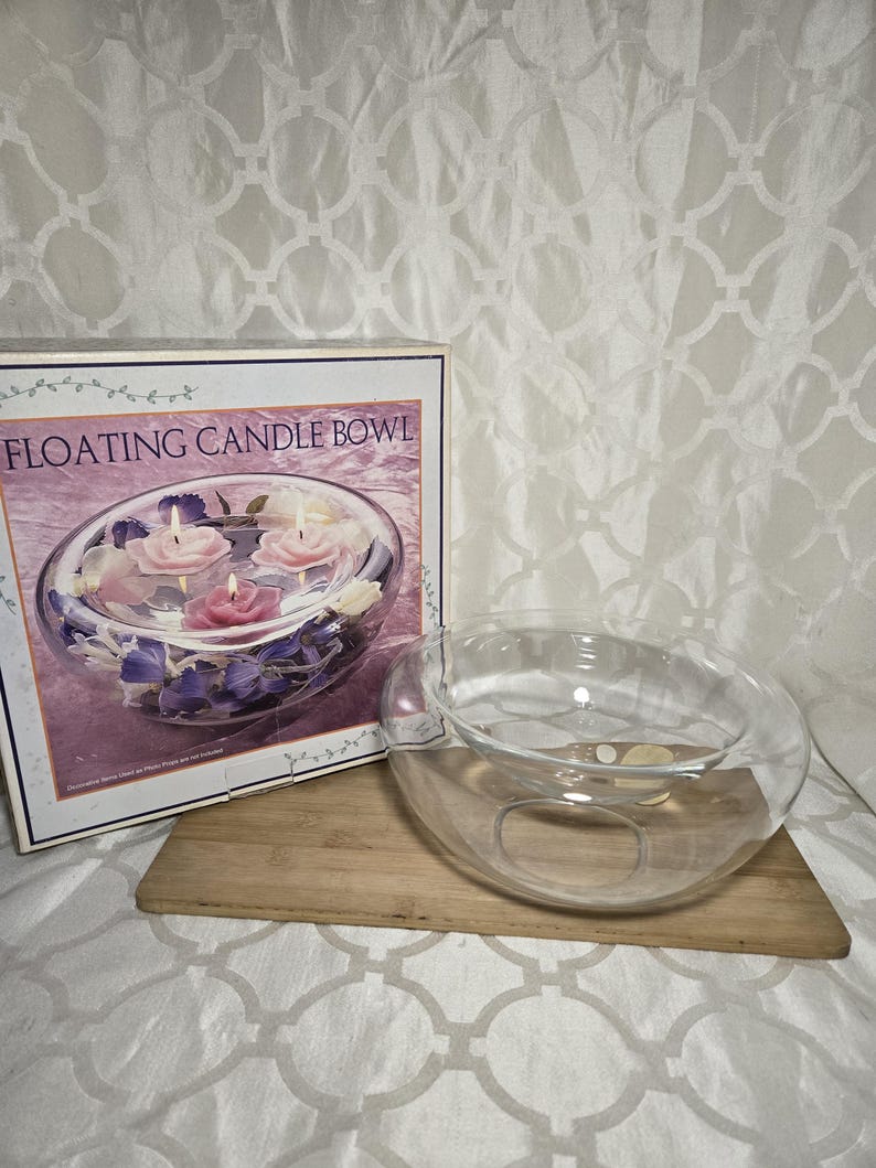 May include: A clear glass floating candle bowl with a box that reads "FLOATING CANDLE BOWL". The bowl is on a wooden board. The box shows the bowl with floating candles and flowers.