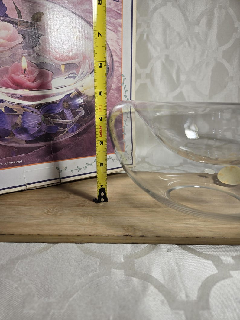 May include: A clear glass decorative bowl with a unique design. The bowl is approximately 8 inches in diameter. The bowl is on a wooden surface. A measuring tape is next to the bowl.
