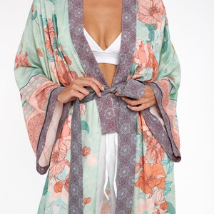May include: A long, flowing green and pink floral print robe with a burgundy trim and a matching tie belt.