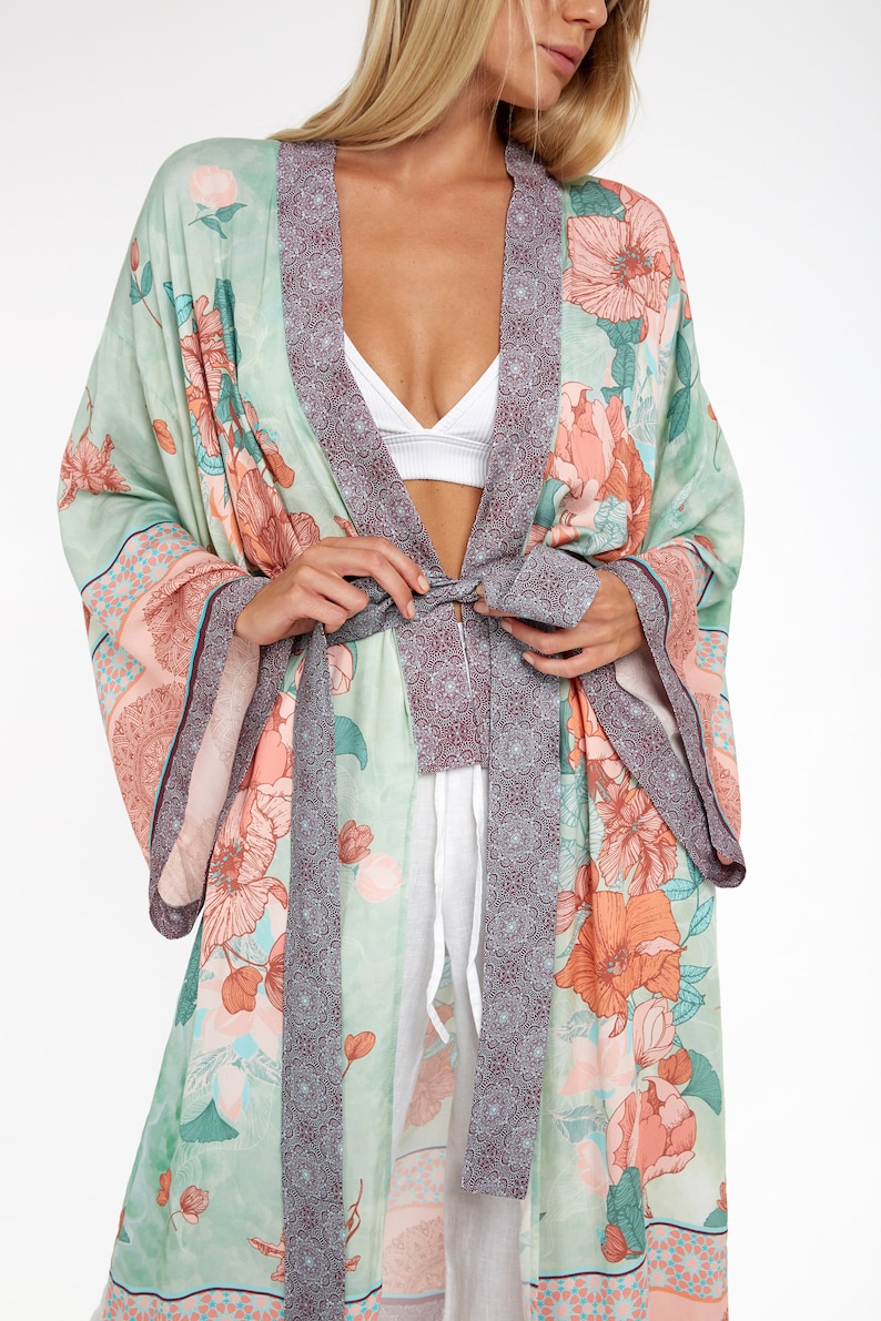 May include: A long, flowing green and pink floral print robe with a burgundy trim and a matching tie belt.