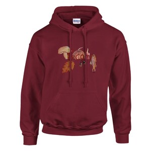 May include: Burgundy hoodie with a front pocket and drawstring. The hoodie features a watercolor illustration of a mushroom, acorn, leaf, garlic, and fish. The brand name "Gildan" is visible on the tag.