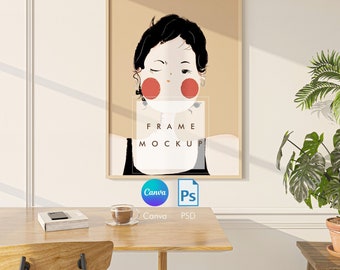 May include: A framed illustration of a woman with red cheeks and black hair, with the text "FRAME MOCKUP" in the bottom center of the frame. The frame is on a white wall with a wooden table and chair in front of it.