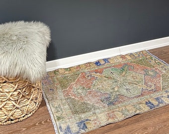 May include: A gray fluffy rug sits on top of a woven basket with a light brown wood floor. A colorful rug with a geometric pattern is on the floor in front of the basket. A framed picture of a bird with the text "A song may sing for sadness" is hanging on a dark gray wall.