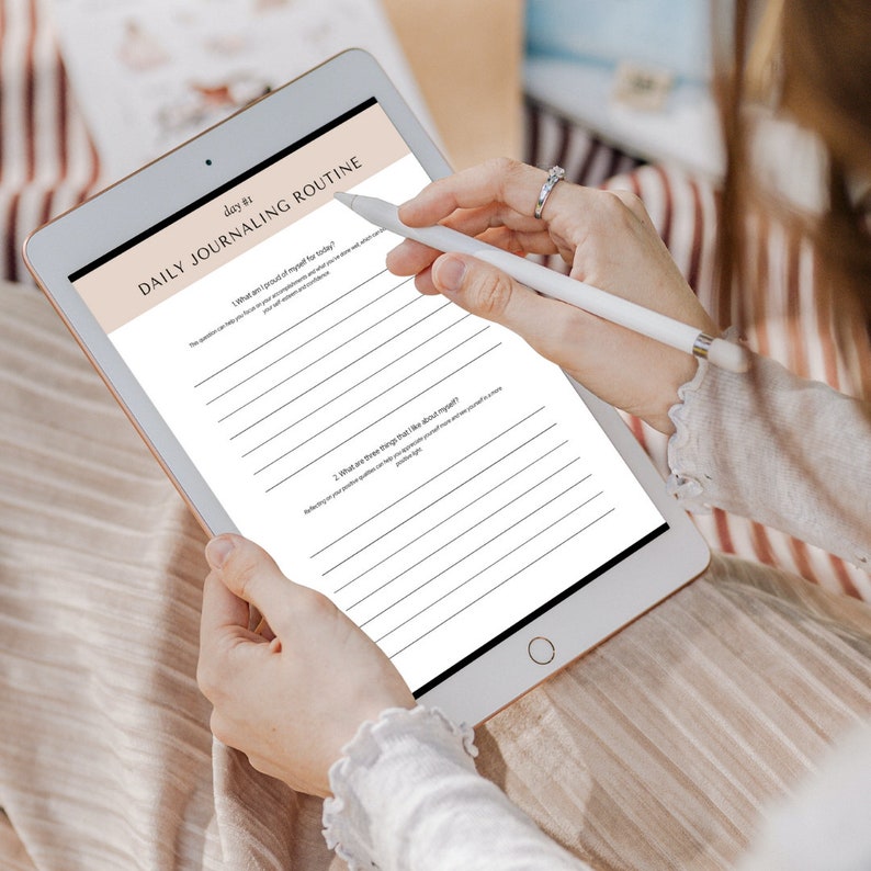 May include: A white tablet with a black screen displaying a daily journaling routine. The screen shows two prompts: "What am I proud of myself for today?" and "What are three things that I feel grateful for?"