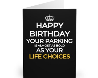 Op de afbeelding: Zwarte felicitatiekaart met witte tekst die luidt "Happy Birthday Your Parking is almost as bold as your Life Choices" met een gouden kroon bovenaan.