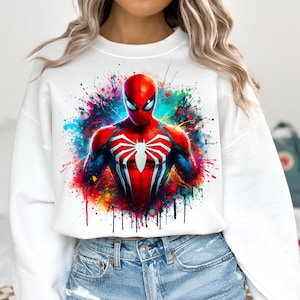 Puede incluir: Sudadera blanca recortada con un dise&ntilde;o de salpicaduras de pintura de colores con un gr&aacute;fico de Spiderman rojo y azul.