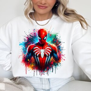 Puede incluir: Sudadera blanca con un dise&ntilde;o de salpicaduras de pintura de colores con un personaje de Spiderman rojo y azul.