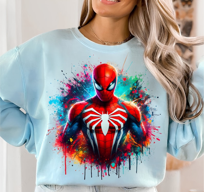 Puede incluir: Una sudadera azul claro con un dise&ntilde;o de salpicaduras de pintura de colores con un gr&aacute;fico de Spiderman rojo y negro.