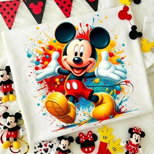 K&ouml;nnte beinhalten: Quadratische, wei&szlig;e Decke mit einem farbenfrohen Mickey Mouse-Motiv und Farbspritzern. Das Bild zeigt Mickey Mouse-Dekorationen, wie Pl&uuml;schtiere und Banner, die ein verspieltes Cartoon-Thema erzeugen.