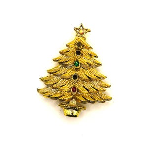 May include: A gold-colored Christmas tree brooch with a star on top and colorful gemstone accents. The brooch features a textured design and a small pot at the base. A festive accessory for the holiday season.