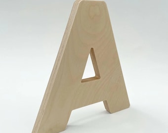 May include: A wooden letter A, made of light-colored plywood. The letter is freestanding and has a simple, modern design.