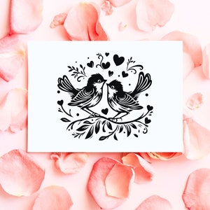 May include: A black and white illustration of two birds facing each other on a branch with hearts and floral accents. The image is on a white card surrounded by pink rose petals.