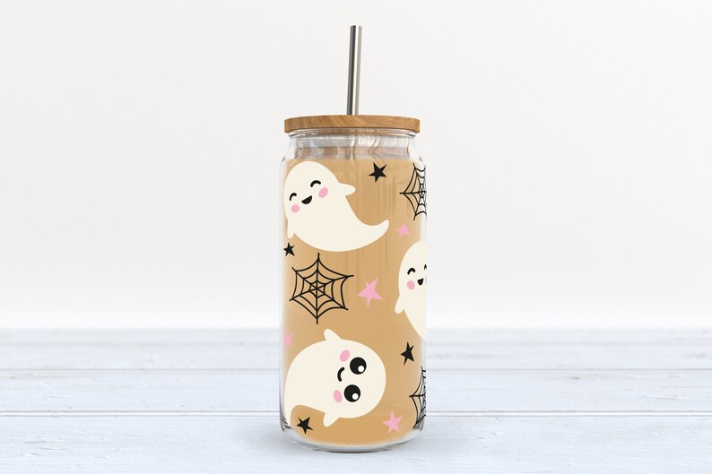 May include: A clear glass tumbler with a brown lid and a straw. The tumbler has a pattern of white ghosts, black spiderwebs, and pink stars on a tan background.