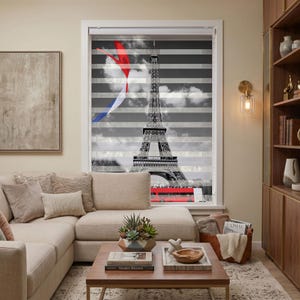 May include: A window roller shade featuring a black and white photographic print of the Eiffel Tower in Paris, accented by a stylized red, white, and blue ribbon graphic. The shade has horizontal stripes and a view of a red bus at the base.