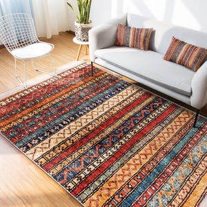 May include: A colorful rug with a striped pattern in shades of red, orange, blue, and beige. The rug has a traditional, tribal design with geometric shapes and intricate details.