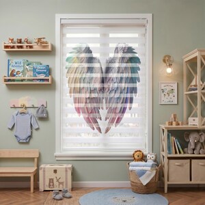 Pode incluir: Uma persiana de janela com um gráfico grande e colorido de asas de anjo em tons pastel suaves de rosa, azul e amarelo. As asas são impressas em tiras de tecido horizontais translúcidas e opacas, criando um efeito de camadas na janela.