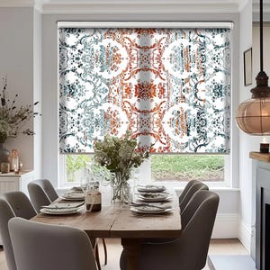 Può includere: Una tenda bianca per finestra con un motivo intricato e colorato di arancione, blu e bianco. La tenda è abbassata e il motivo è visibile attraverso la finestra. La tenda è in una sala da pranzo con un tavolo e sedie in legno.