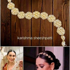 May include: A gold headband with white stones, known as a "sheeshpatti", is worn by a woman with dark hair. The headband is a traditional Indian accessory.
