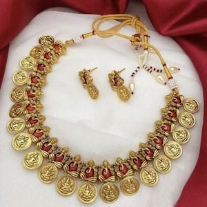 May include: Gold necklace with red and gold beads and gold coin pendants featuring a deity. Matching earrings are included.