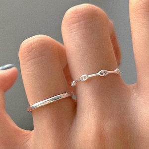 May include: A white ceramic mug with a black handle and the text "But First, Coffee" in a black, handwritten-style font. The mug is on a white surface.