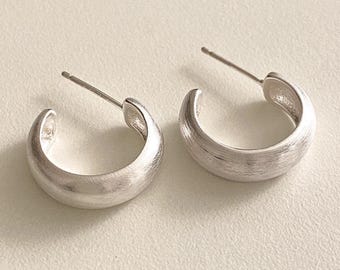 Pode incluir: Um par de brincos de argola de prata com acabamento escovado. Os brincos são simples e elegantes, e seriam uma ótima adição a qualquer coleção de joias.
