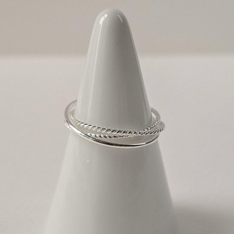 Interlocking silver ring with three fine bands of different finishes, offering a modern, minimalist take on the classic Russian ring.