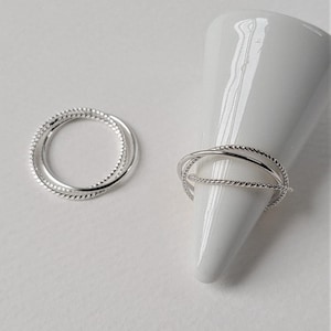 Sterling silver trinity ring combining three ultra-thin bands with contrasting finishes, crafted into a sculptural minimalist silhouette.