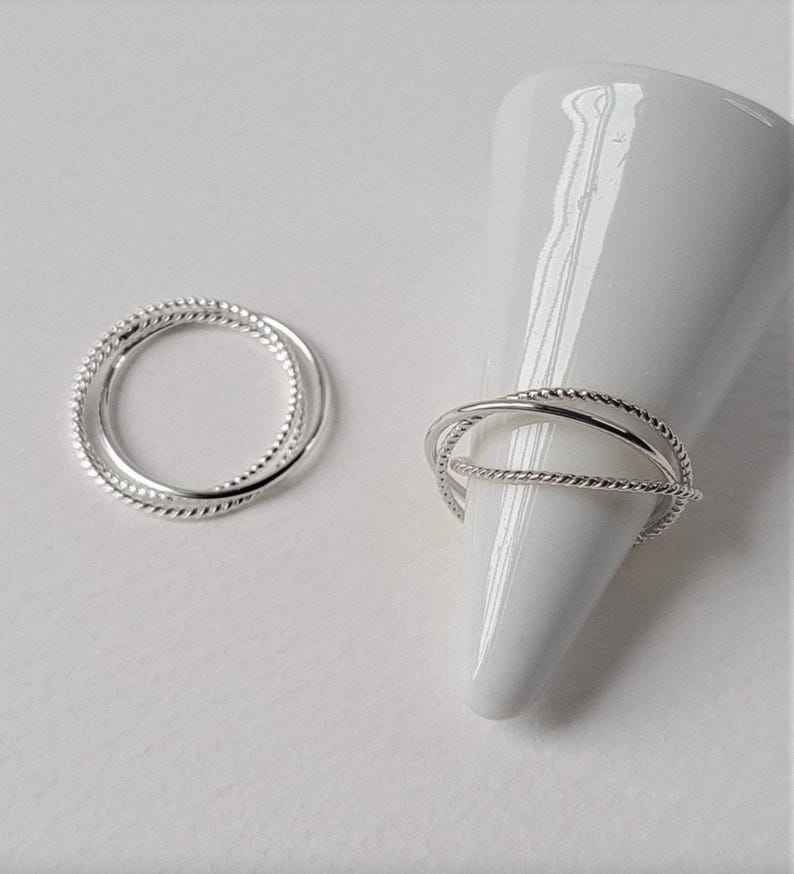 Sterling silver trinity ring combining three ultra-thin bands with contrasting finishes, crafted into a sculptural minimalist silhouette.