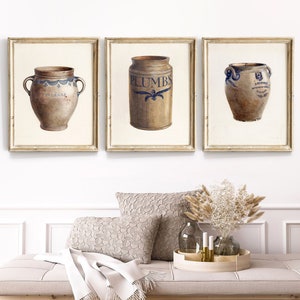 Puede incluir: Tres tinajas de gres de estilo vintage con diseños pintados en azul y blanco. Las tinajas están etiquetadas con "For Pears", "Plumbs" y "L. Richmond's Golden Wheat Flour".