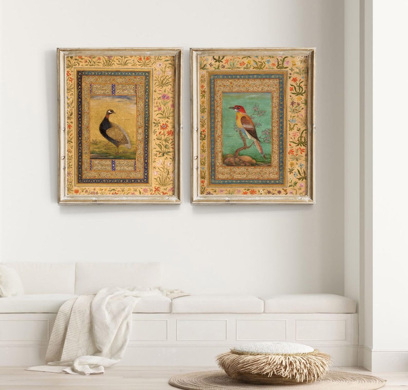 May include: Two framed prints with ornate gold frames and intricate floral borders. The prints feature detailed illustrations of birds, one a pheasant and the other a colorful bird with a long beak, on a light blue background.