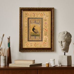May include: A framed print of a detailed illustration of a bird with a gold background and a floral border. The bird is brown and black with a long neck and a long tail. The frame is ornate and has a gold finish.