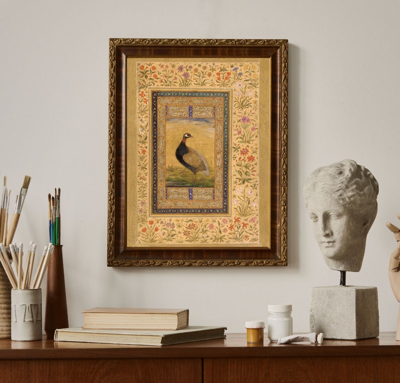 May include: A framed print of a detailed illustration of a bird with a gold background and a floral border. The bird is brown and black with a long neck and a long tail. The frame is ornate and has a gold finish.