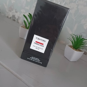 May include: A black box with a white label that reads "TOM FORD FABULOUS EAU DE PARFUM 100 ML". The box also has a smaller white label that reads "EAU DE PARFUM VAPORISATEUR SPRAY 3.4 FL. OZ/OZ. LIQ/100 ml e".