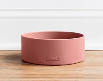 May include: A pink silicone pet bowl with the word "TROUGH" embossed on the front.