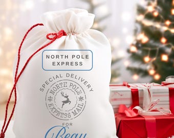 May include: White fabric gift bag with red drawstring and a gray stamp that says "Special Delivery North Pole Express Mail" with a reindeer illustration. The bag also has a label that says "North Pole Express" and the name "Beau" in blue cursive.