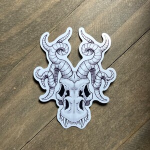 May include: A black and white illustration of a skull with horns. The skull has a detailed design with intricate lines and curves. The horns are curled and twisted, giving the skull a menacing appearance.