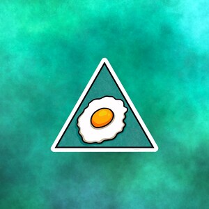 Pode incluir: Um adesivo triangular branco com fundo azul e uma imagem de desenho animado de um ovo frito com gema amarela.