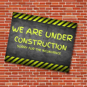 Puede incluir: Un letrero rectangular con el texto "WE ARE UNDER CONSTRUCTION" en letras amarillas, con las palabras "SORRY FOR THE INCONVIENCE" debajo. El letrero tiene rayas diagonales amarillas y negras y está colocado contra una pared de ladrillos rojos.